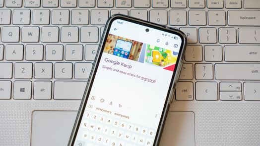 Một ghi ch&uacute; Google Keep hiển thị tr&ecirc;n điện thoại đặt tr&ecirc;n b&agrave;n ph&iacute;m m&aacute;y t&iacute;nh x&aacute;ch tay
